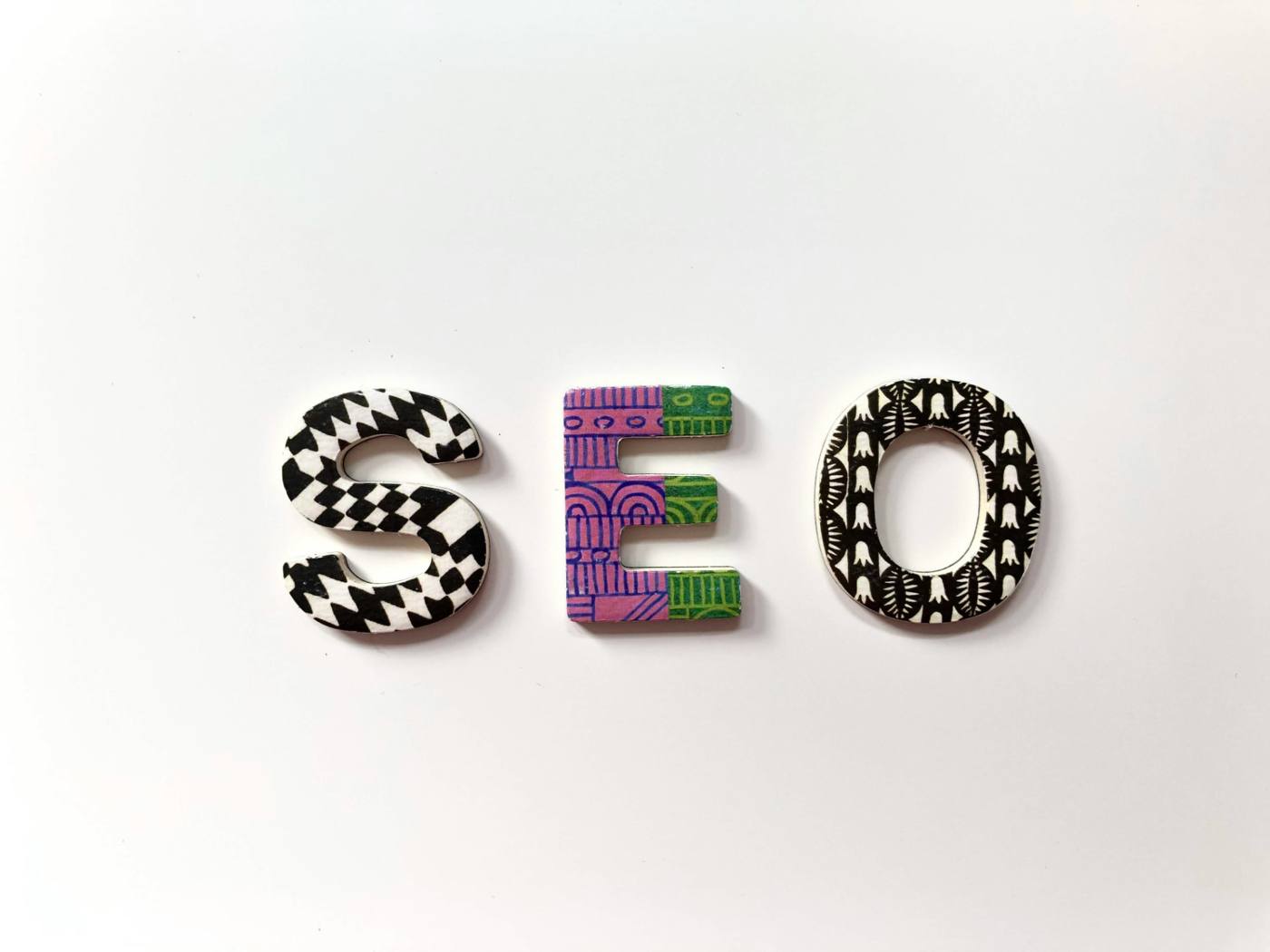 Wooden letters spelling SEO arranged on a white background