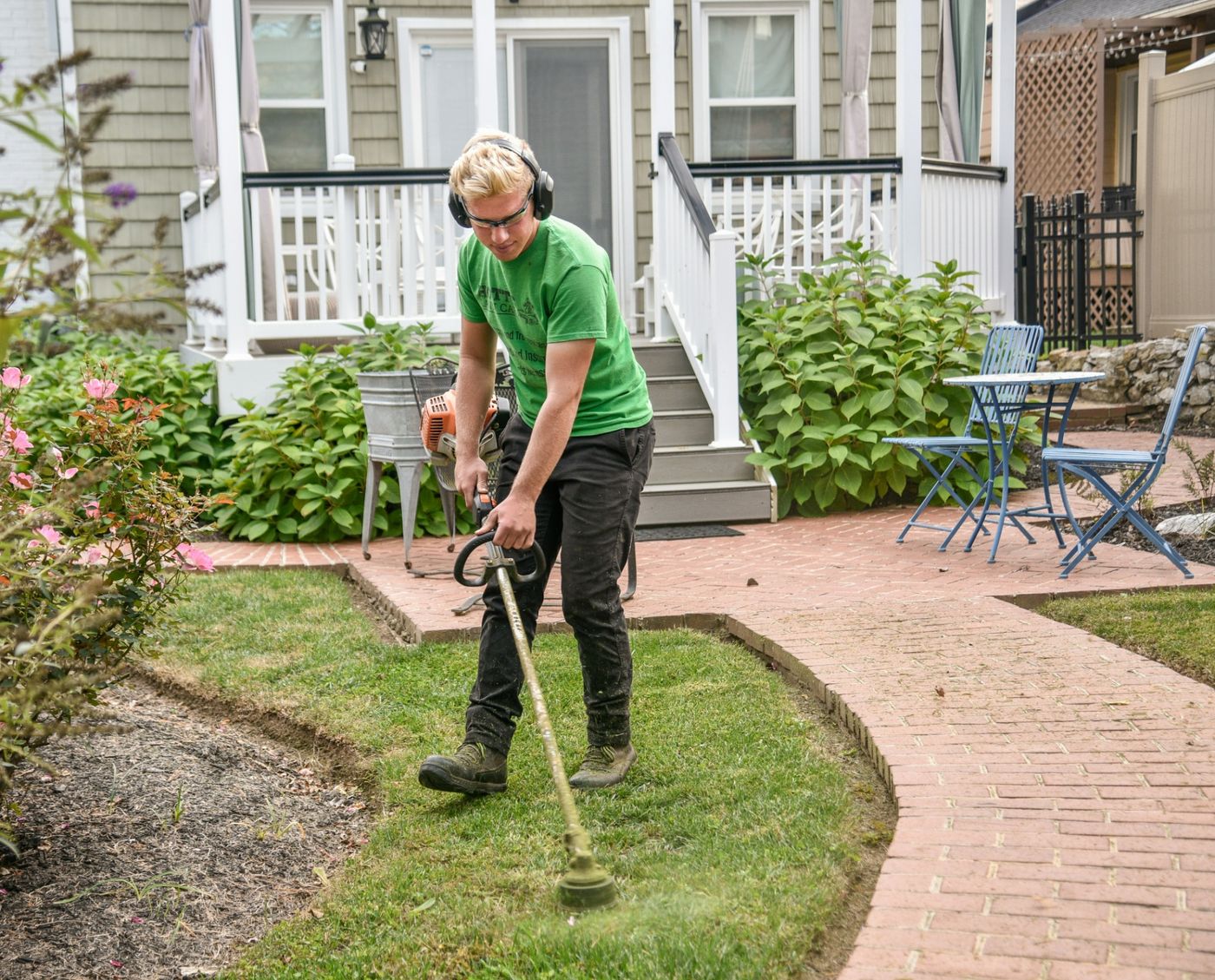 Professional lawn care technician in branded uniform edging grass in a residential front yard, the type of landscaping business that ranks well in Google local search