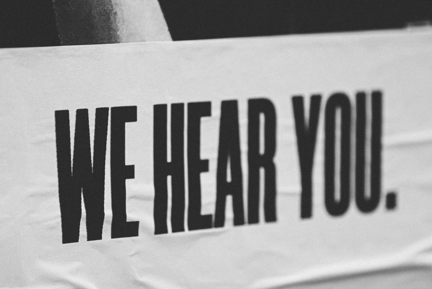 Black and white sign reading We Hear You, representing businesses that respond to customer reviews